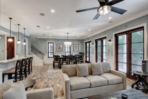 A spacious living area with a sofa, a coffee table, a dining table with chairs, a chandelier, and a ceiling fan. - 2 Bedroom condo at Fisherman’s Wharf inside Sandestin Golf and Beach Resort (Miramar Beach)