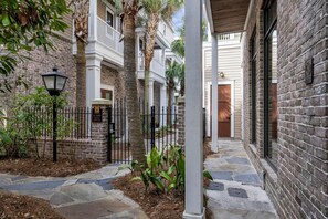 A courtyard with a stone pathway, a black metal fence, and a building with a brick facade. - 2 Bedroom condo at Fisherman’s Wharf inside Sandestin Golf and Beach Resort (Miramar Beach)