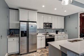 A modern kitchen with white cabinetry, stainless steel appliances, and a central island. - 2 Bedroom condo at Fisherman’s Wharf inside Sandestin Golf and Beach Resort (Miramar Beach)