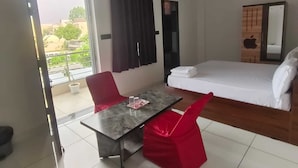 Una camera d'albergo con un letto, un tavolo da pranzo con sedie, una ventola a soffitto e una finestra con tende.