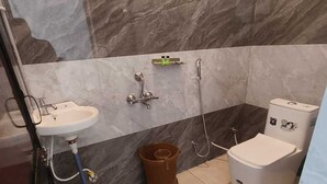 Un bagno con lavandino, water, doccia e un secchio per mocio.