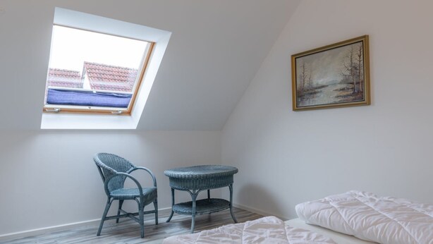 A bedroom with a skylight, a bed, a chair, a small table, and a painting on the wall. - Geraumiges Ferienhaus fur Familie im Hafendorf Muritz Rechlin (Rechlin)