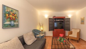 A living room with a sofa, a coffee table, a television, and a painting on the wall. - Geraumiges Ferienhaus fur Familie im Hafendorf Muritz Rechlin (Rechlin)