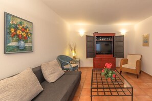 A living room with a sofa, a coffee table, a television, and a painting on the wall. - Geraumiges Ferienhaus fur Familie im Hafendorf Muritz Rechlin (Rechlin)