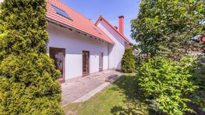 A single-story house with a red-tiled roof, a front door, and a small porch area. - Geraumiges Ferienhaus fur Familie im Hafendorf Muritz Rechlin (Rechlin)
