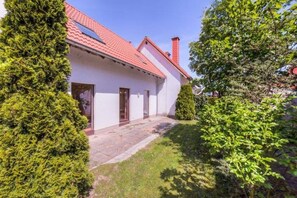 A single-story house with a red-tiled roof, a front door, and a small porch area. - Geraumiges Ferienhaus fur Familie im Hafendorf Muritz Rechlin (Rechlin)