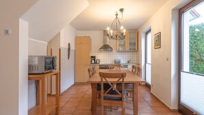 A compact kitchen with a dining table, chairs, a microwave, and a chandelier. - Geraumiges Ferienhaus fur Familie im Hafendorf Muritz Rechlin (Rechlin)