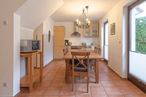 A compact kitchen with a dining table, chairs, a microwave, and a chandelier. - Geraumiges Ferienhaus fur Familie im Hafendorf Muritz Rechlin (Rechlin)