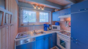 Cocina compacta con gabinetes de madera, un lavamanos, un microondas y una estufa.