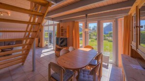 Un interior de madera con zona de comedor, televisor y vista al exterior.
