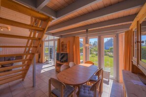 Ein Holzinnenraum mit Essbereich, Fernseher und Blick ins Freie.
