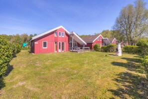 Ein rotes Haus mit einem großen Vorgarten und einer Rutsche im Hintergrund.