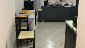 Une pièce de taille modeste comprenant un lit, une petite table avec des chaises, un téléviseur et un luminaire au plafond.