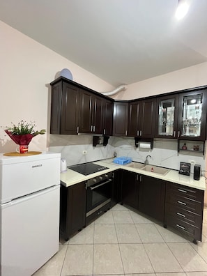 A compact kitchen with dark cabinets, a white countertop, a built-in oven, and a coffee machine. - Charming apartment in marvelous Vlorë (Vlorë)