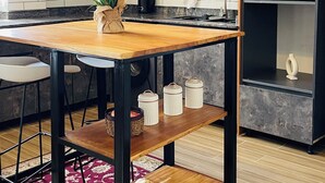 Une cuisine moderne avec des meubles en bois, un pare-feu en marbre, une table à manger en bois et un four encastré.
