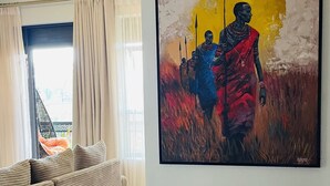 Un salon moderne avec un grand tableau, un canapé et une vue par la fenêtre.