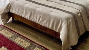 Une chambre à coucher avec un lit en bois, un tapis à motifs et un tableau accroché au mur.