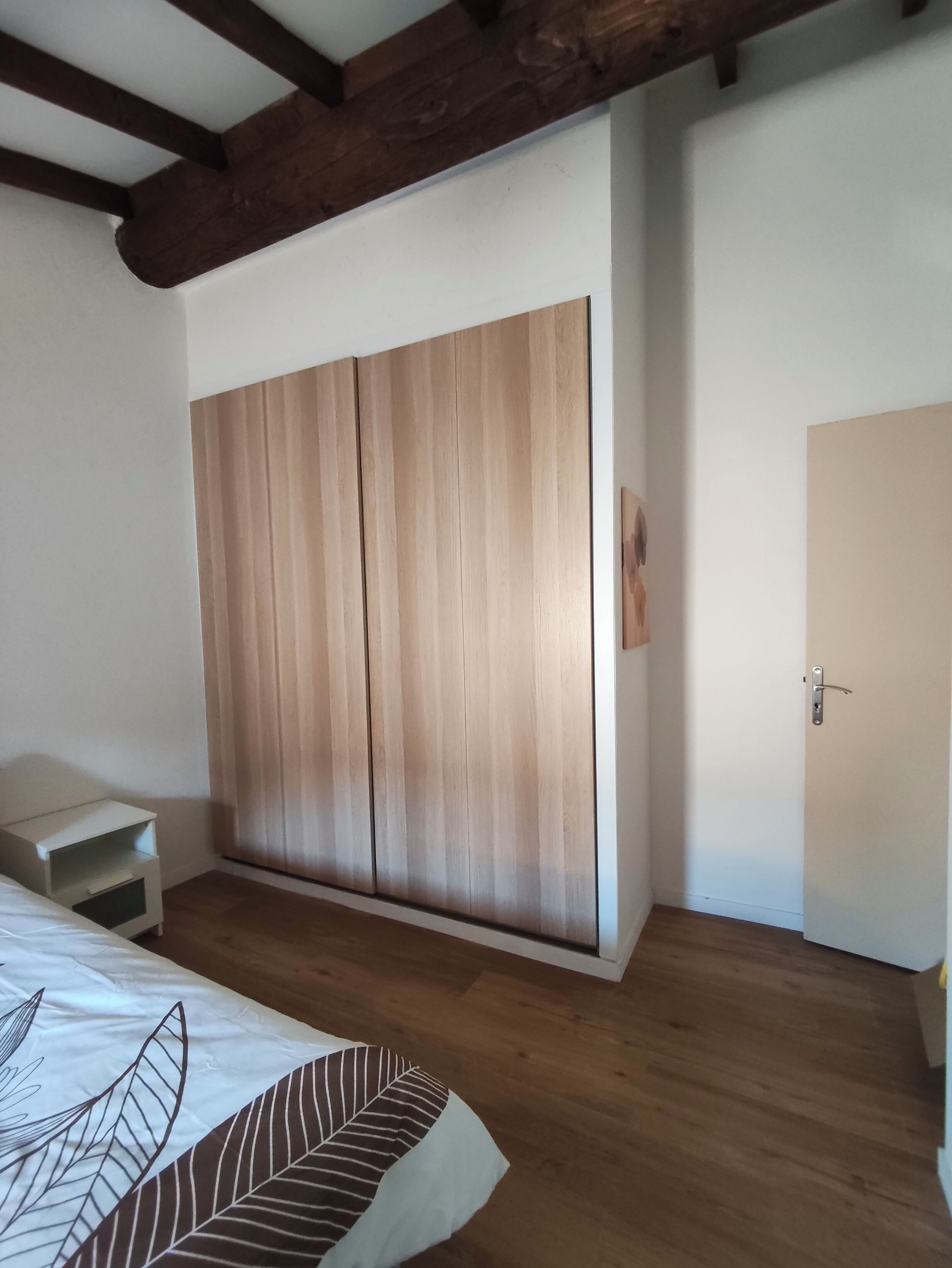 Ein Schlafzimmer mit Holzschrank, Nachttisch und Tür.