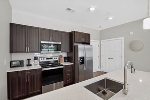 A modern kitchen with dark wood cabinets, stainless steel appliances, and a white countertop. - Parkview Greer 2BR Retreat (Greer)