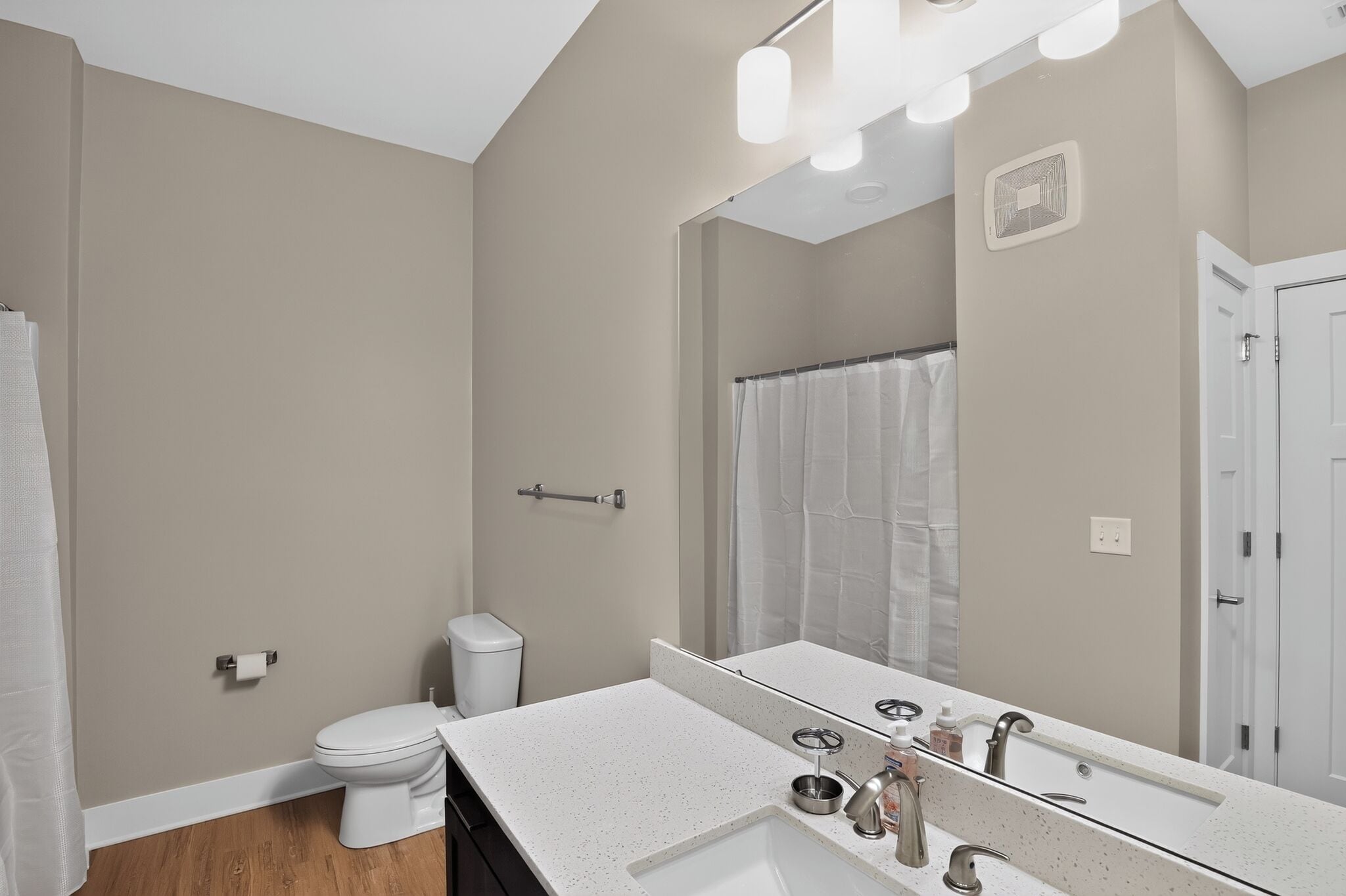 Een badkamer met toilet, wastafel, spiegel en douchegordijn.