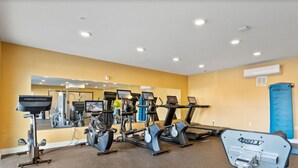Un gimnasio con diversos equipos de ejercicio, incluyendo cintas de correr, bicicletas estáticas y pesas libres.