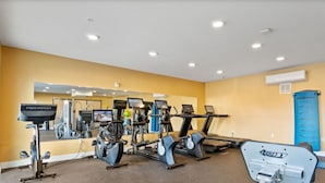 Ein Fitnessstudio mit verschiedenen Trainingsgeräten, darunter Laufbänder, Ergometer und Kurzhanteln.