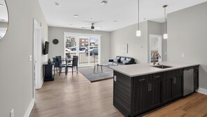 A modern kitchen with a large island, dark cabinetry, and pendant lighting. - Homey 2BR with Great Space (Greer)