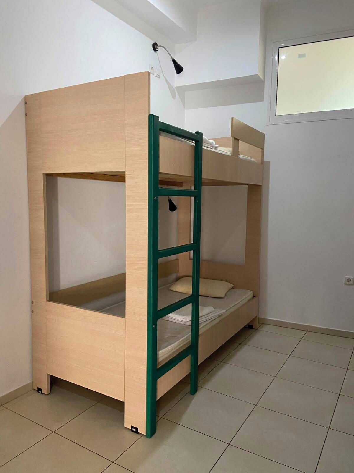 A bunk bed with a ladder, a desk, and a window.