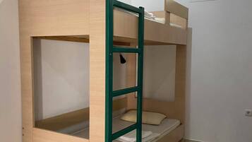 A bunk bed with a ladder, a desk, and a window.