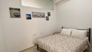 A bedroom with a bed, a large mirror, and wall-mounted artwork.