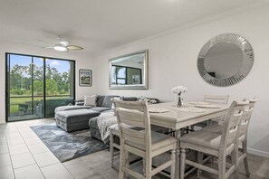 A dining area with a table, chairs, a sofa, and a large mirror.