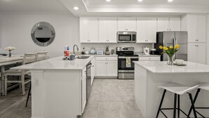 A modern kitchen with white cabinetry, a central island, a microwave, a refrigerator, and a sink. - New To Market- All New Furnishings- Lakewood National Golf Condo with Resort Amenities (Bradenton)