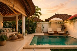 Ein Poolbereich mit überdachter Sitzecke, Liegestühlen und Pool.