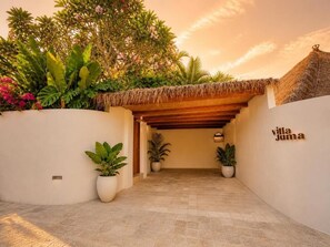 Ein Villa-Eingang mit Strohdach, Blumentöpfen und einem Schild mit der Aufschrift 'villa Juma'.