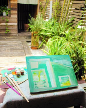 A painting on a table with art supplies, surrounded by greenery. - Ẩn Studio - Hidden Gem - Walk to Ben Thanh Market (Thành phố Hồ Chí Minh)