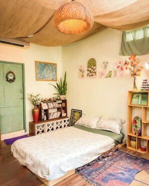 A bedroom with a bed, a bookshelf, a wall with framed pictures, and a hanging light fixture. - Ẩn Studio - Hidden Gem - Walk to Ben Thanh Market (Thành phố Hồ Chí Minh)
