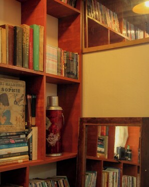 A bookshelf with various books and a thermos. - Ẩn Studio - Hidden Gem - Walk to Ben Thanh Market (Thành phố Hồ Chí Minh)