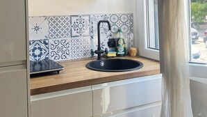 Eine Küche mit einem schwarzen Spülbecken, weißen Schränken und einem Fliesenspiegel mit Muster.