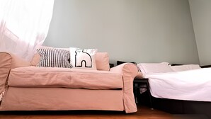Ein Zimmer mit einer Schlafcouch, einem Bett und einem Nachttisch.