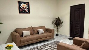 Ein Wohnzimmer mit Sofa, Couchtisch, Teppich, Topfpflanze und Deckenventilator.