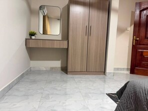 Un dormitorio con armario, mesita de noche y espejo.