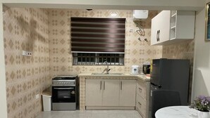 A compact kitchen with a gas stove, oven, sink, and a refrigerator.