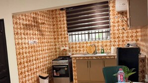 Una cocina compacta con estufa a gas, horno y ventana con persianas.