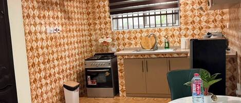 A compact kitchen with a gas stove, oven, and a window with blinds.