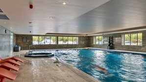 Une piscine intérieure à l’eau claire, un jacuzzi et un sol carrelé.