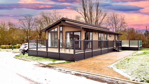 Un bâtiment d’un seul étage, doté d’un toit plat, de grandes fenêtres et d’un espace extérieur couvert, délimité par une clôture.
