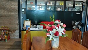 A wooden dining table with a vase of flowers in the center.