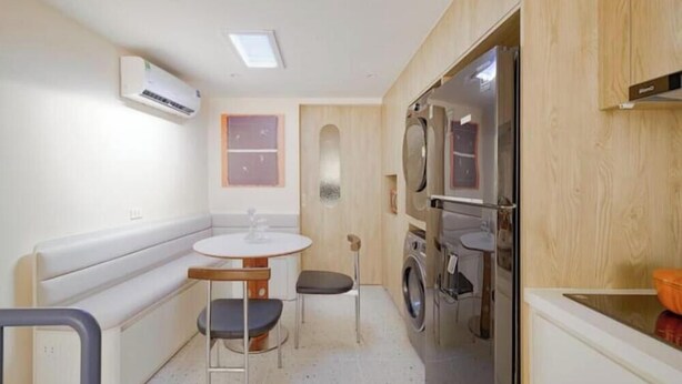 A compact kitchen with a washing machine, a bench, and a small dining table. - Blue & Oak • Upscaled APT• Airport Pickup• Beer St (Hà Nội)