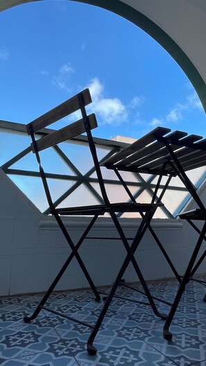 Ein Zimmer mit Oberlicht, einem gemusterten Boden und einem Metallstuhl.