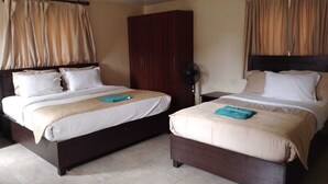 A hotel room with two beds, a wardrobe, a fan, and curtains. - Bar BnB Spa and Barber (Nairobi)